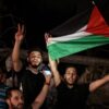 People wave the Palestinian flag as they celebrate in the street following a ceasefire brokered by Egypt between Israel and the two main Palestinian armed groups in Gaza on 21 May, 2021