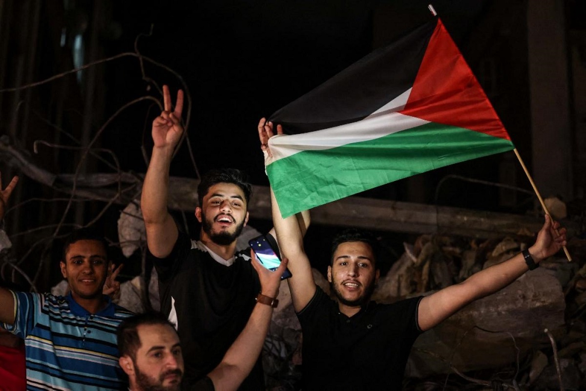 People wave the Palestinian flag as they celebrate in the street following a ceasefire brokered by Egypt between Israel and the two main Palestinian armed groups in Gaza on 21 May, 2021
